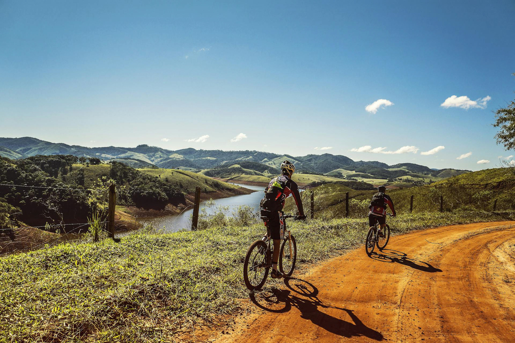 Mountain bikers on a dirt road overlooking the rocky mountains and valleys.
